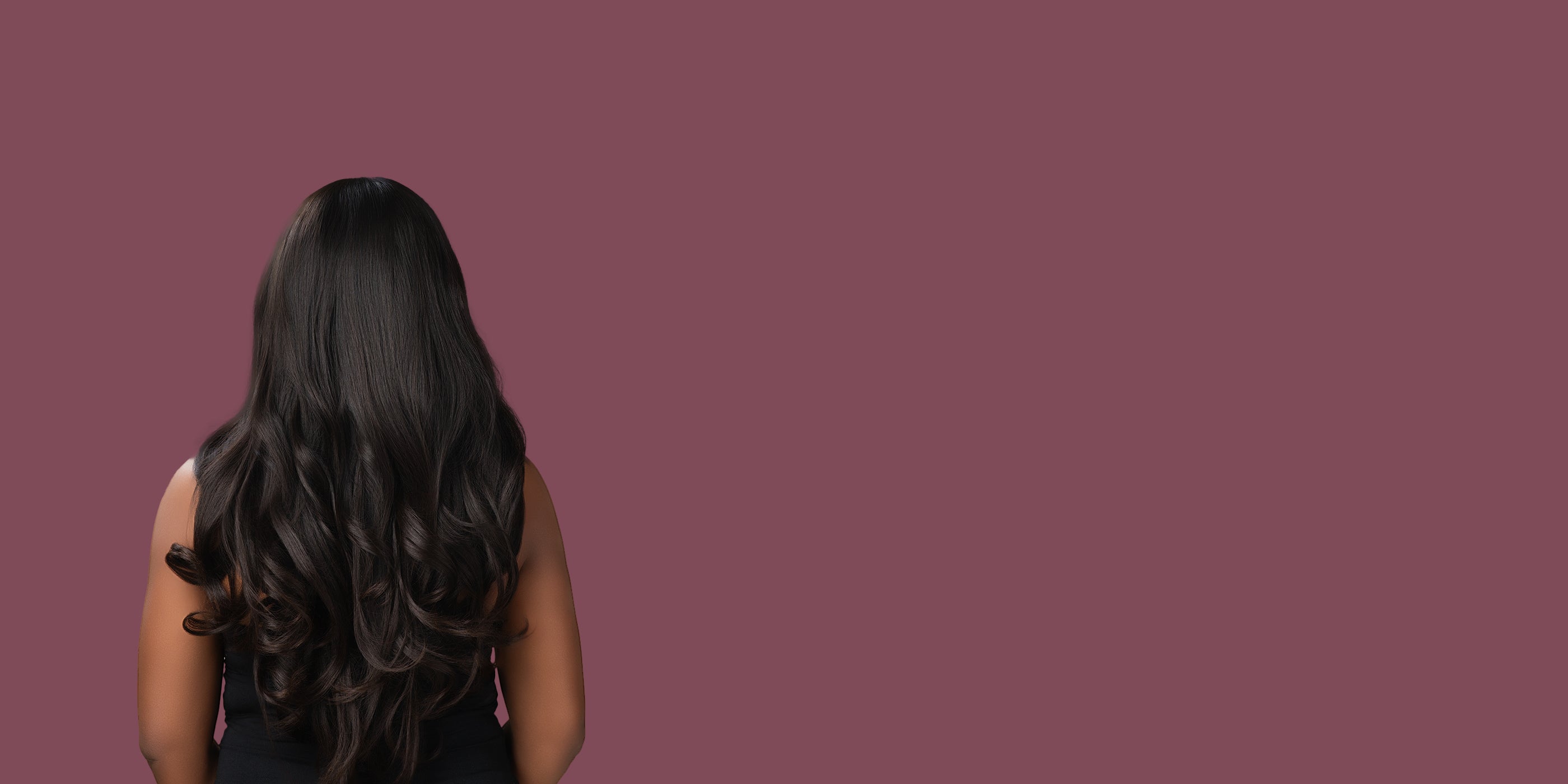 Woman with long, wavy hair on a solid purple background